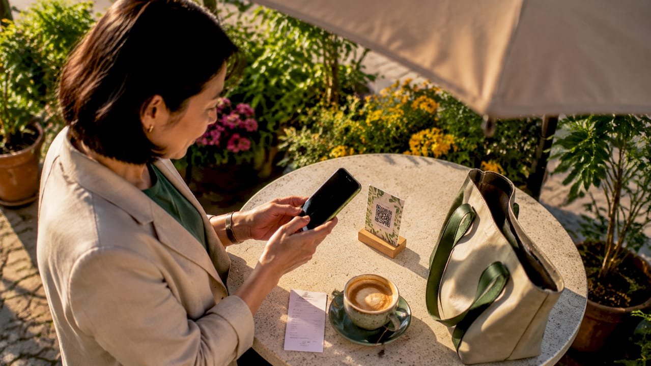 Woman scanning QR code at café table