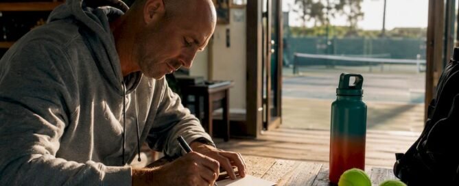 Tennis coach writing thank-you note at desk