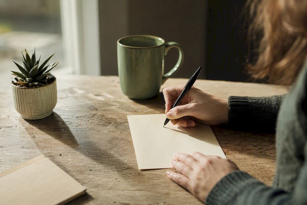 Hand writing thank-you note at desk