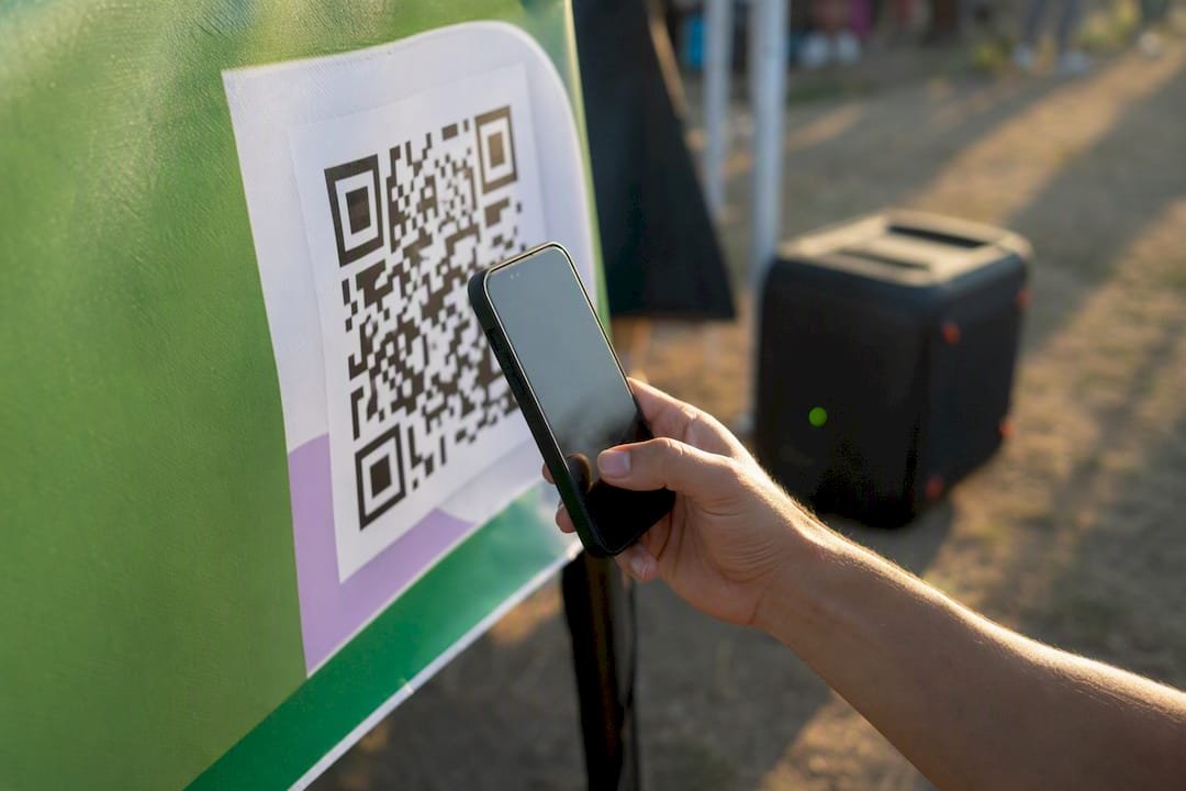 Hand scanning QR code with smartphone at event